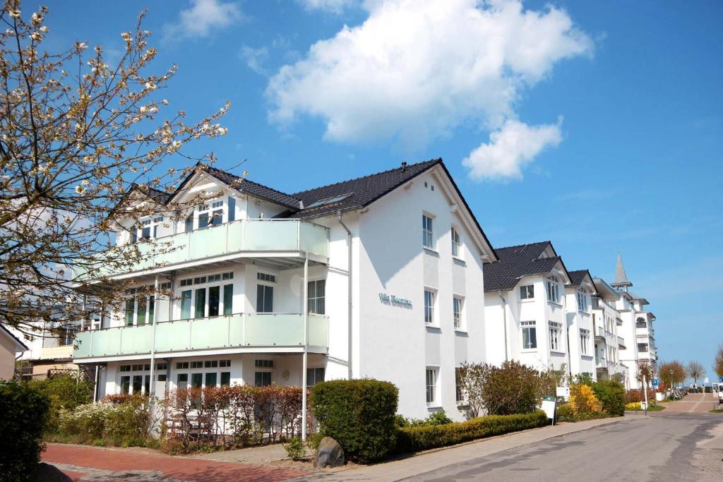 a white building with a black roof on a street at Villa Meernixe by Rujana in Binz