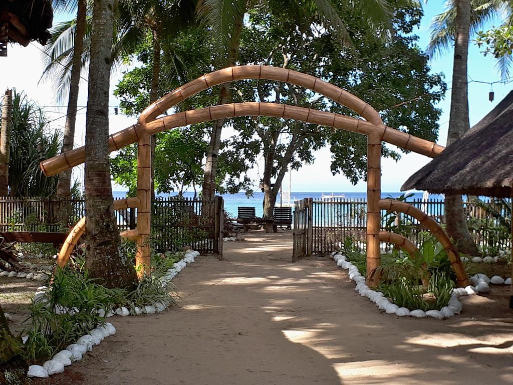 a wooden archway in a park with a bench at Big BamBoo Beach Resort Sipalay in Sipalay