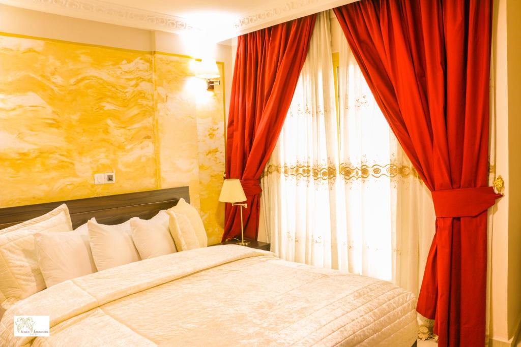 a bedroom with a bed with red curtains and a window at Noubou International Hotel in Douala