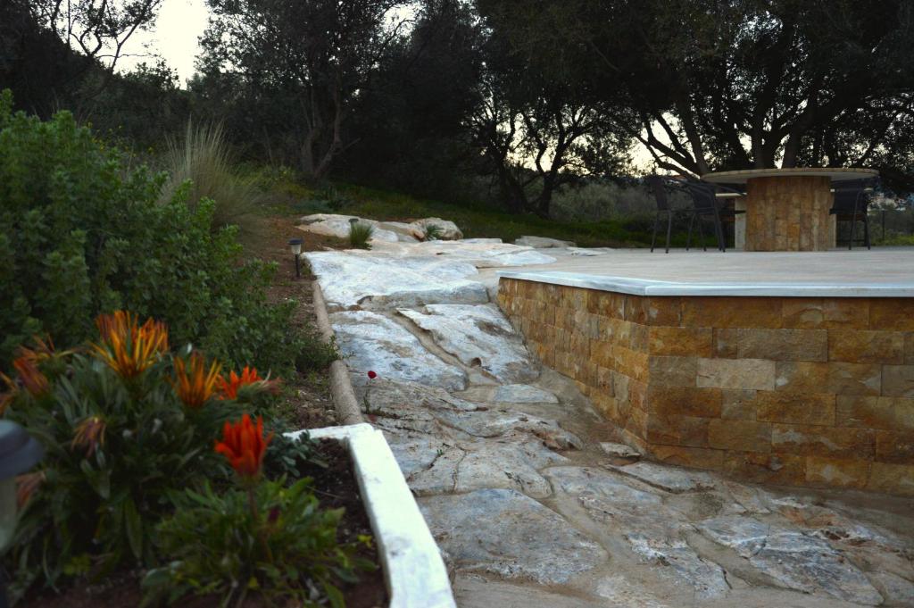 a garden with flowers and a stone wall at Marathon Eco Stay in Marathon