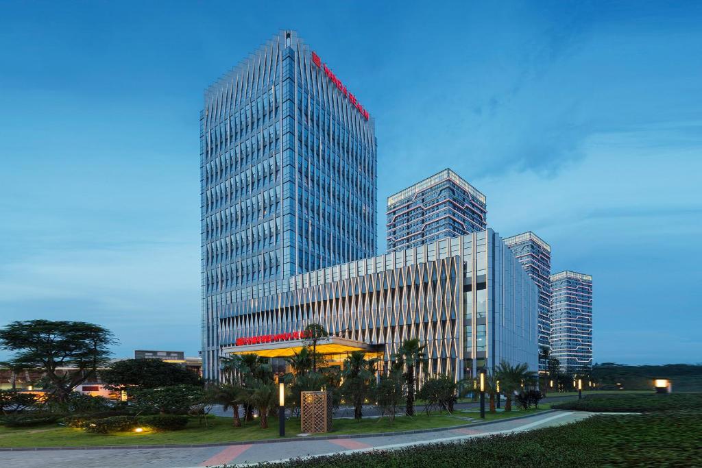 a tall glass building with a red sign on it at Wanda Realm Guangzhou Zengcheng in Zengcheng