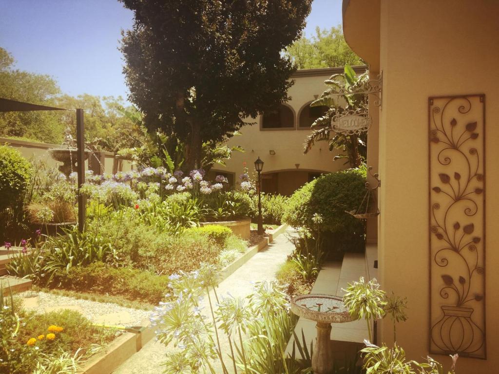 a garden with flowers and a building with a walkway at Dunton Guest House in Johannesburg