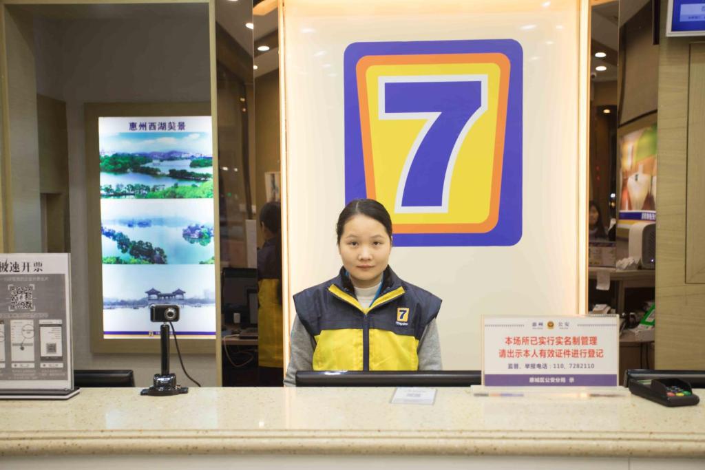 una mujer parada detrás de un mostrador en una tienda en 7Days Inn Huizhou West Lake, en Huizhou