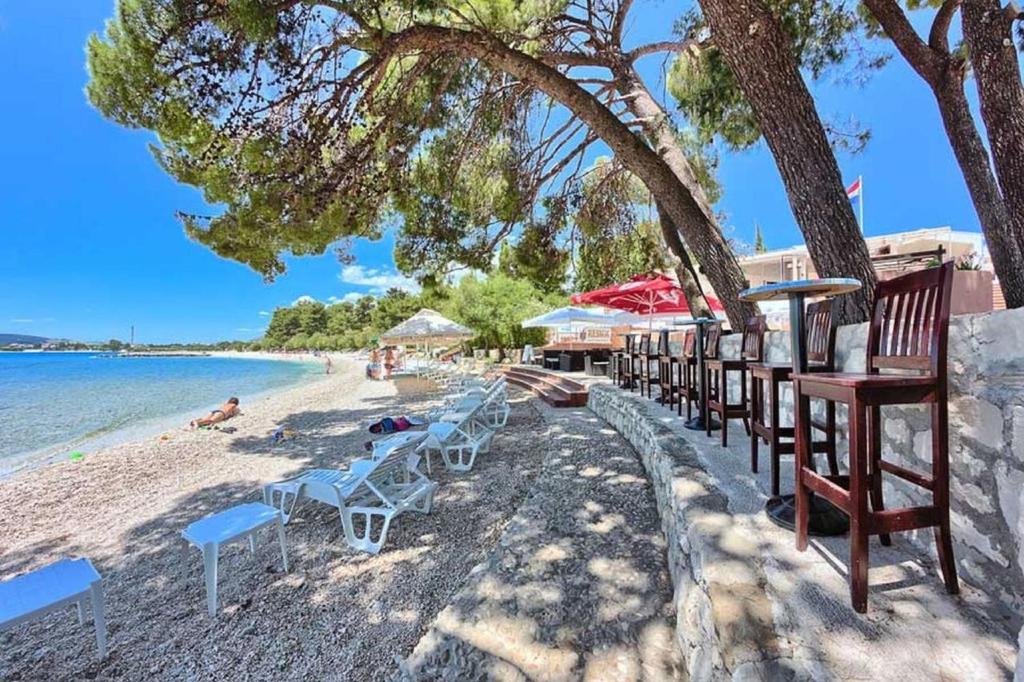 una playa con sillas y sombrillas y el océano en Apartments & Rooms Seaside, en Kaštela