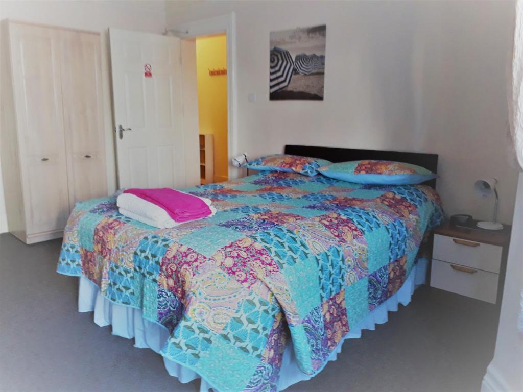 a bedroom with a bed with a colorful comforter and pillows at Sunrise Apartments in Llandudno