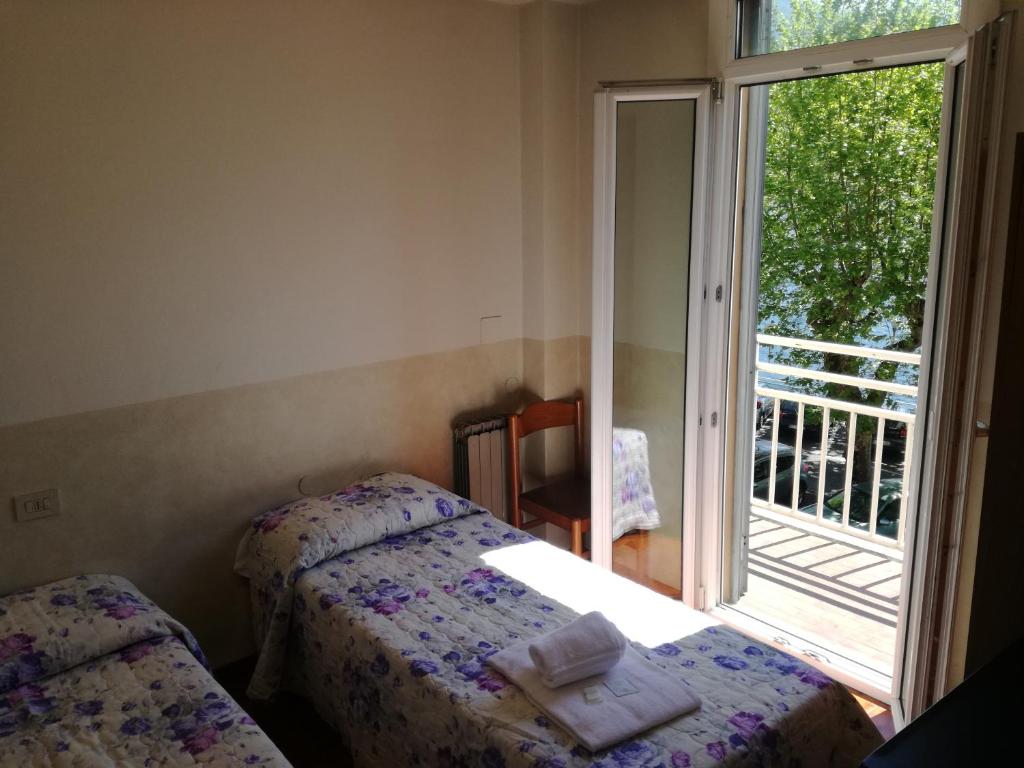 a bedroom with two beds and a window with a balcony at Hotel Belvedere in Lovere