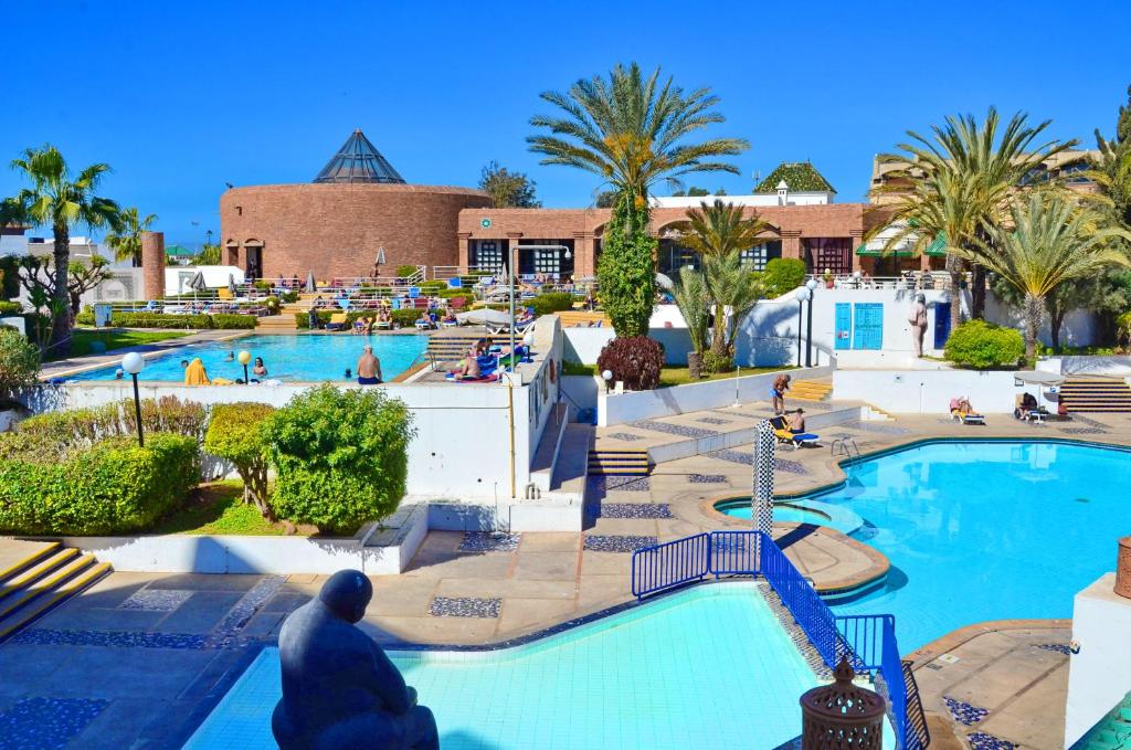 un complexe avec une grande piscine bordée de palmiers dans l'établissement El Pueblo Tamlelt, à Agadir