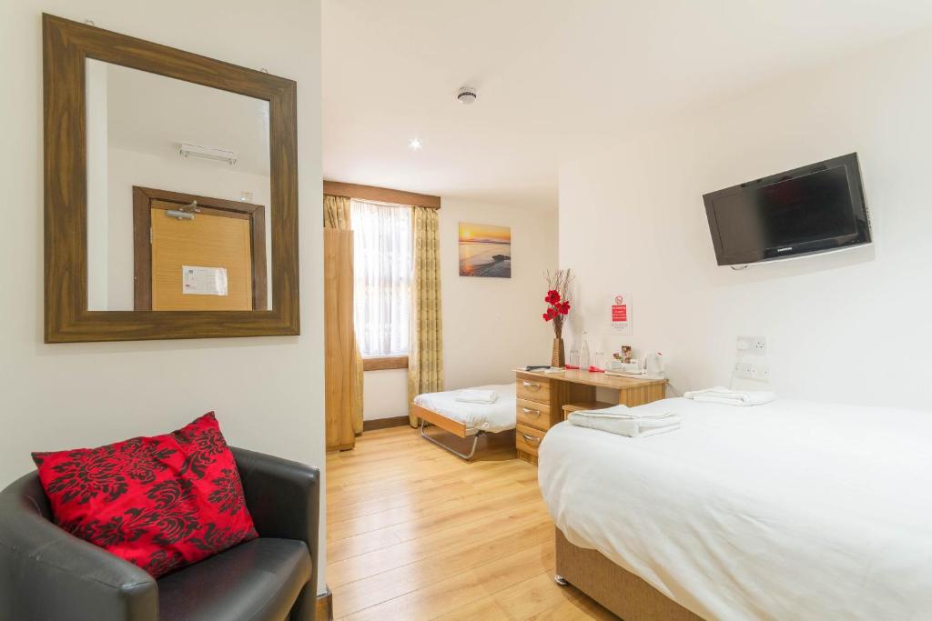 1 dormitorio con cama, silla y espejo en Brick Lane Hotel en Londres