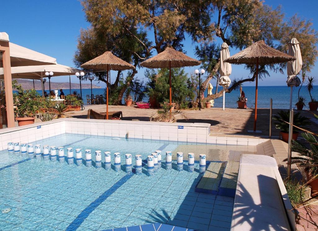 a swimming pool with umbrellas next to the ocean at Kato Stalos Mare in Stalos