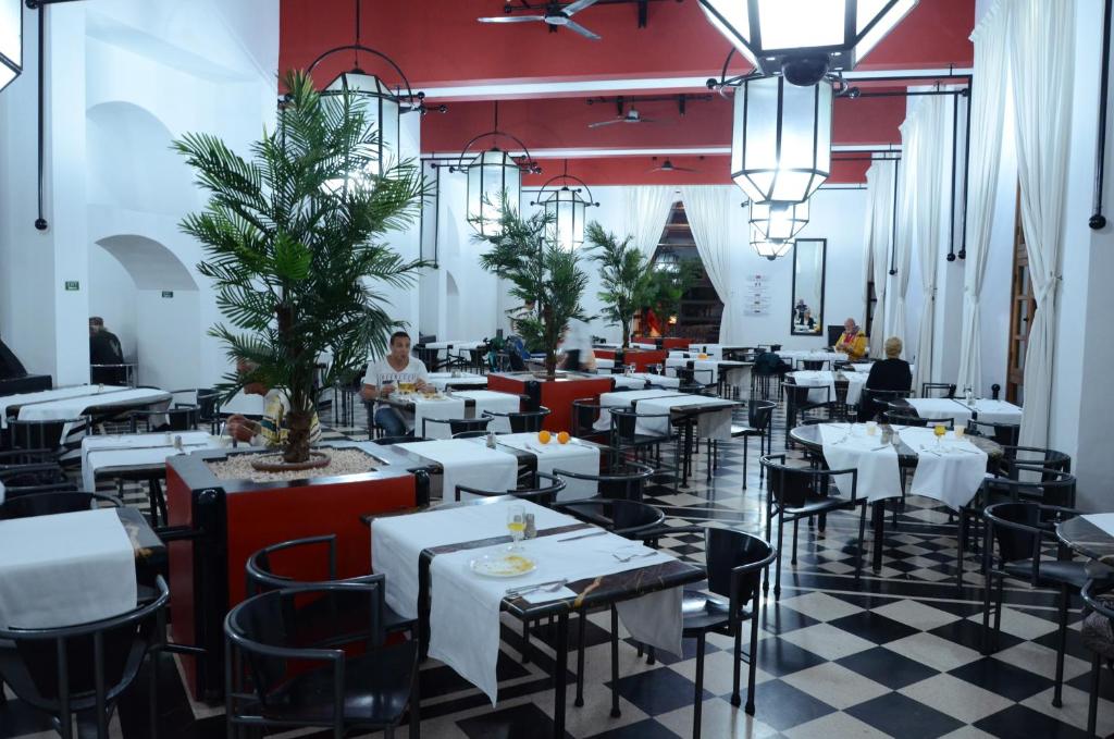 un restaurant avec des tables blanches et des chaises noires dans l'établissement El Pueblo Tamlelt, à Agadir