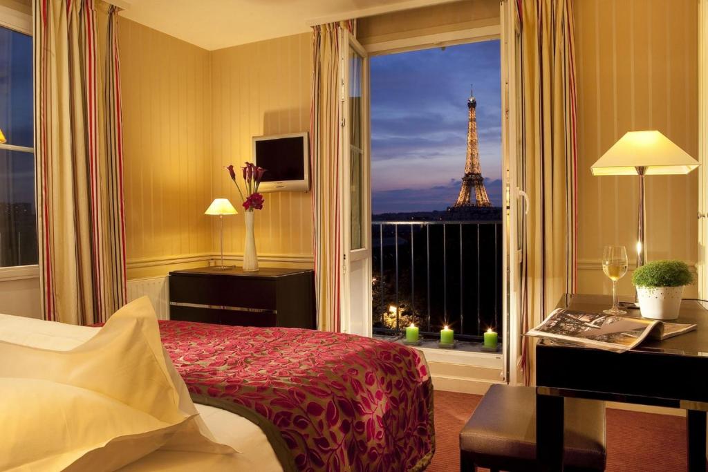 um quarto com uma cama e uma janela com a torre Eiffel em Hotel Duquesne Eiffel em Paris
