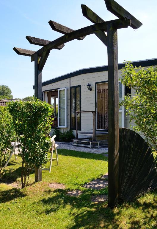 a house with a wooden pergola in the yard at Chalet Ketjil in Oostvoorne