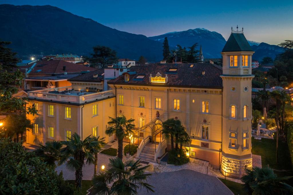 a large building with a clock tower at night at Villa Italia Luxury Suites and Apartments in Arco