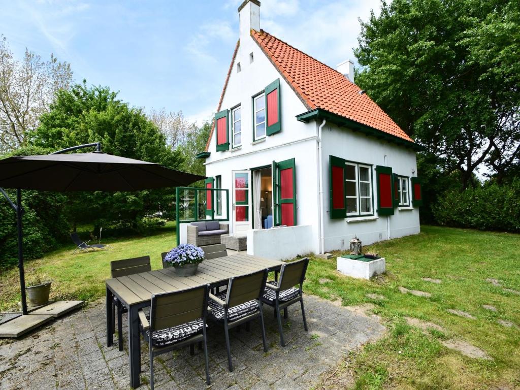アウウドルプにあるQuintessential holiday home in Ouddorp with gardenのテーブルと椅子と傘が備わる家