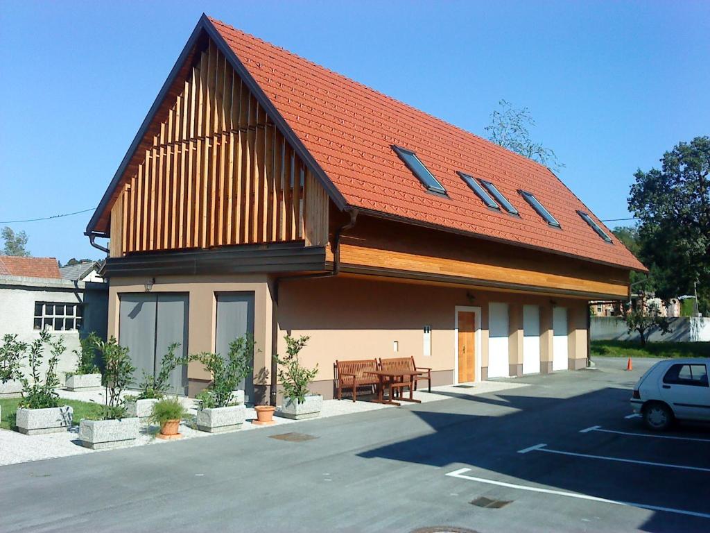 a building with an orange roof with a car parked in front at Guest accomodation Klancar in Ig