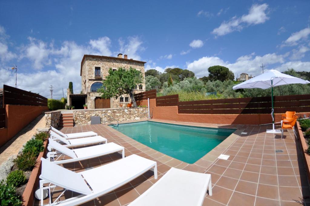 een zwembad met witte ligstoelen en een huis bij Cal Petit in Santa Cristina d'Aro