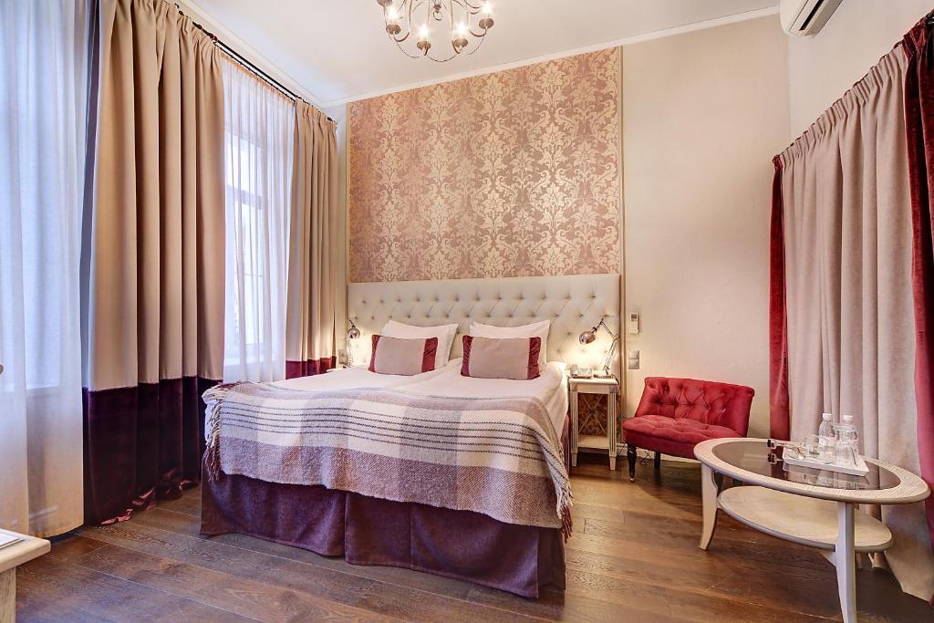 a hotel room with a bed and a red chair at Pushka INN hotel in Saint Petersburg