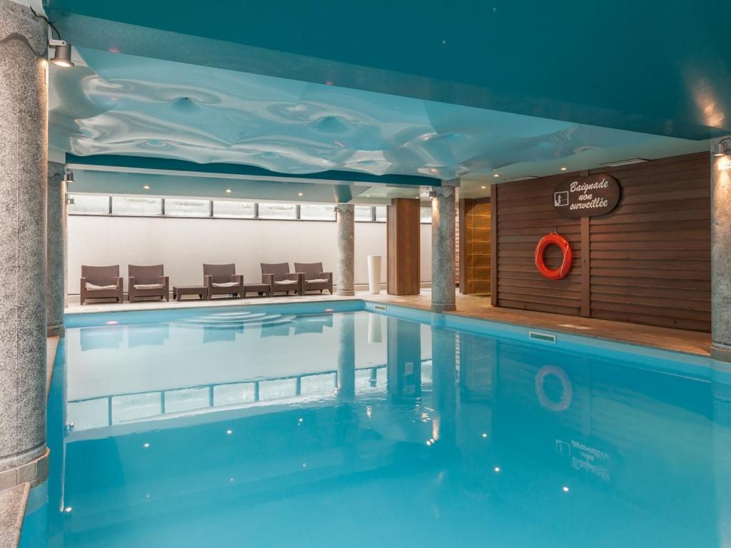 a large swimming pool in a building with chairs at Residence La Ginabelle - maeva Home in Chamonix-Mont-Blanc