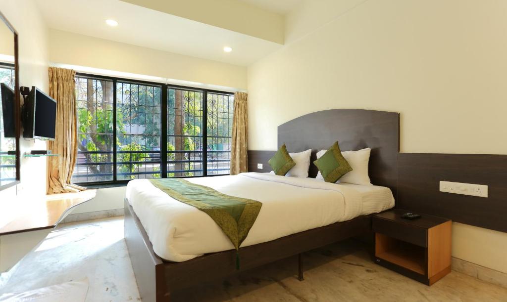 1 dormitorio con 1 cama grande y ventanas grandes en Itsy By Treebo - Hill View Ex, en Pune