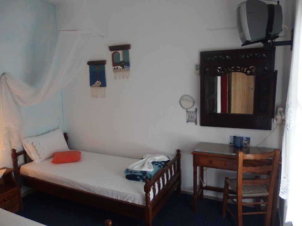 a small bedroom with a bed and a mirror at Pension Titika in Katapola