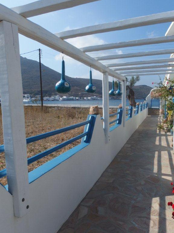 a row of blue benches on a wall with a view of the ocean at Pension Titika in Katapola
