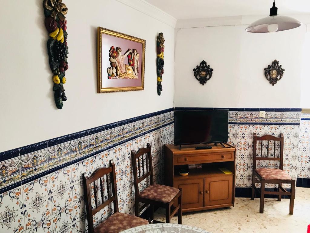 sala de estar con TV y sillas en Casa Rural Setenil, en Setenil