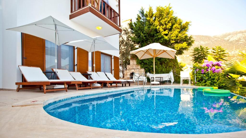 a swimming pool with chairs and umbrellas next to a building at Stunning Seaviews in Kalkan
