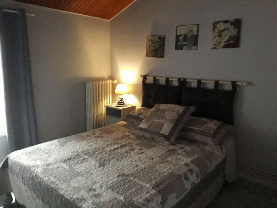 a bedroom with a bed and a lamp on a table at La petite auberge in Châtelraould-Saint-Louvent