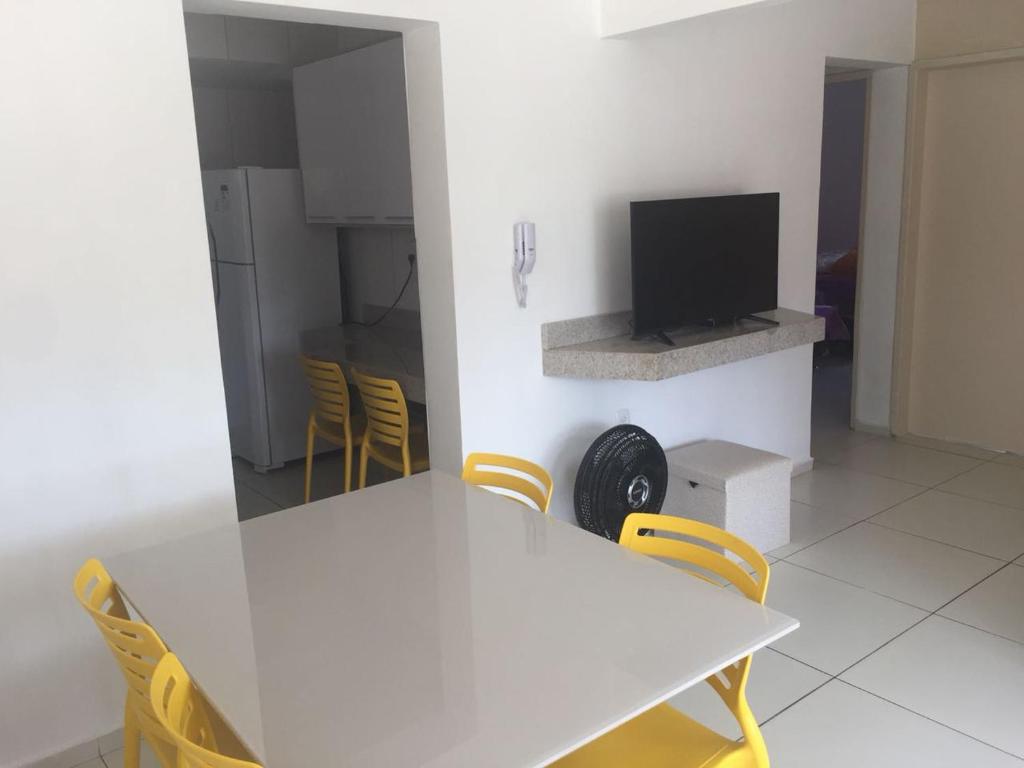 comedor con mesa blanca y sillas amarillas en Apartamento San Lorenzo, en Maceió