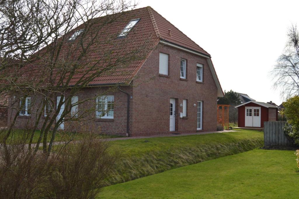 una gran casa de ladrillo rojo con un patio verde en Deichperle Nessmersiel, en Nessmersiel