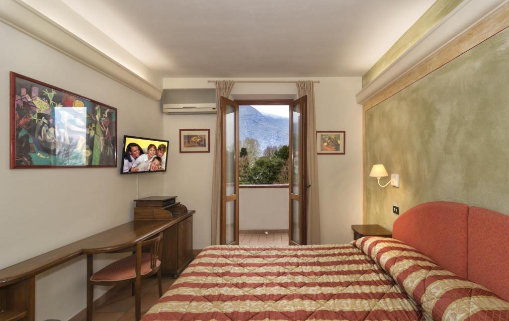a bedroom with a bed and a desk and a window at Hotel Ristorante da Carlos in Santa Maria del Giudice