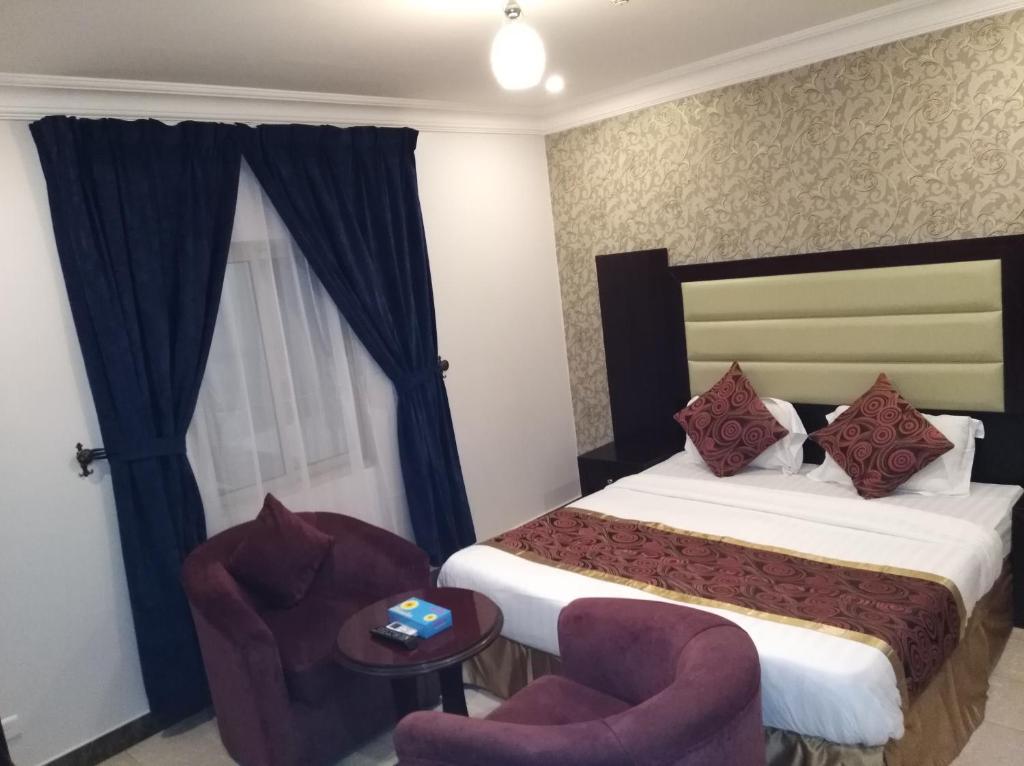 a hotel room with a bed and a chair at Mkani Apartment in Al Khobar