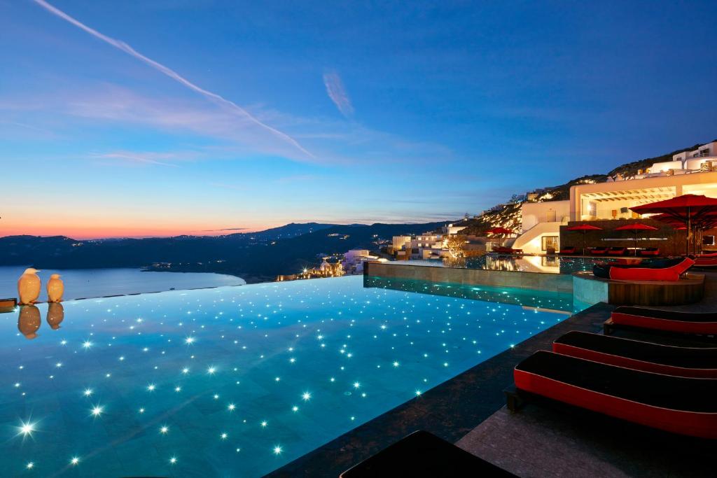 ein Pool mit Lichtern am Abend in der Unterkunft Myconian Avaton, a Member of Design Hotels in Elia