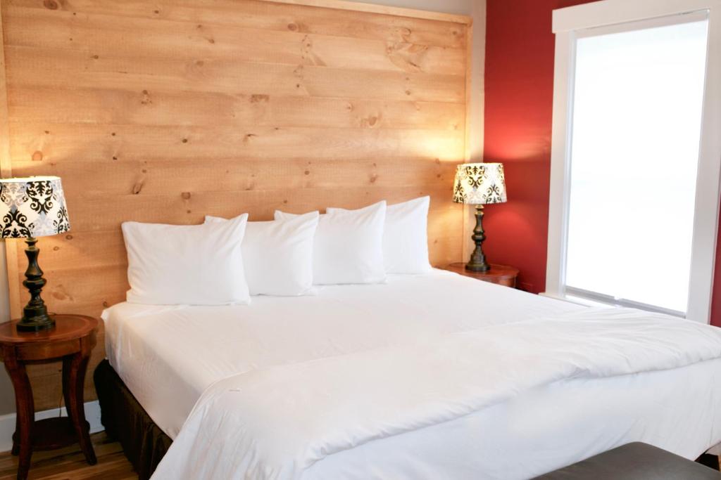 a bedroom with a large white bed with two lamps at Inn at Kampfires in Dummerston Center