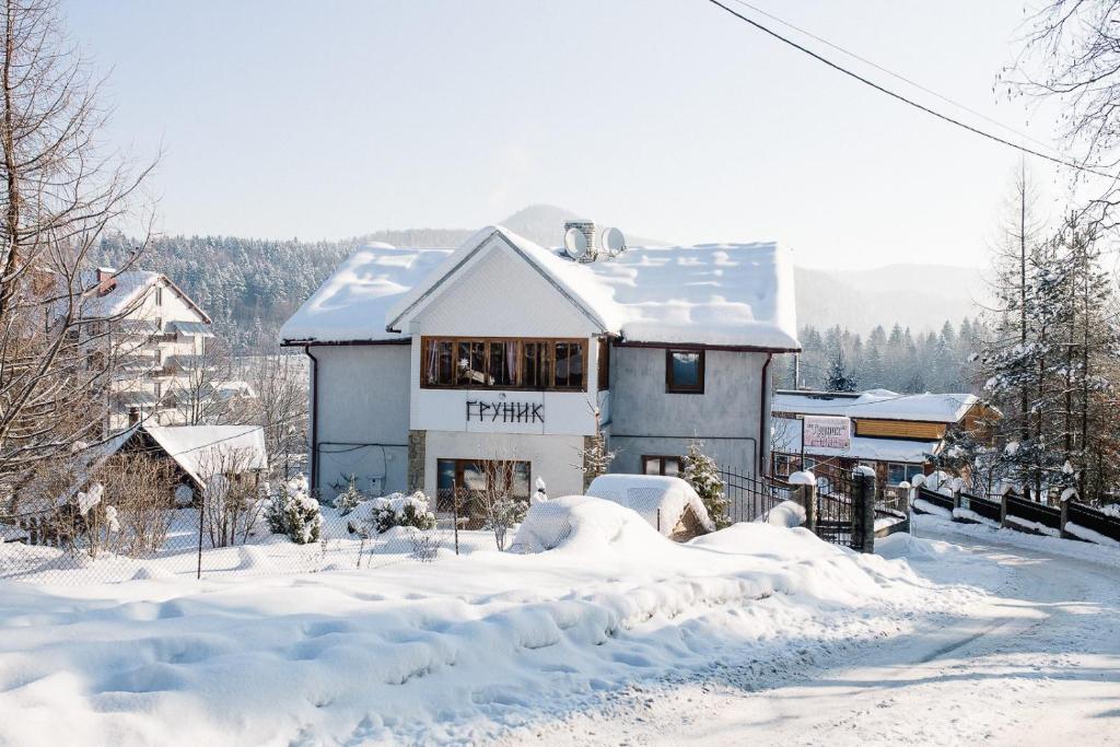 una casa en la nieve con suelo cubierto de nieve en Guest House Grunyk, en Yaremche
