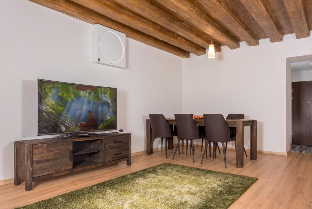 ein Esszimmer mit einem Tisch und Stühlen sowie einem Flachbild-TV in der Unterkunft Casa Nicolae Luxury Suites in Sibiu
