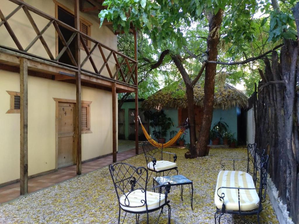 eine Terrasse mit Stühlen und einer Hängematte vor einem Haus in der Unterkunft Hotel Loro Tuerto in Santa Cruz de Barahona