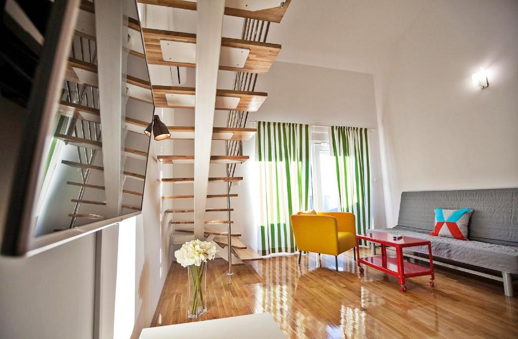 ein Wohnzimmer mit einer Wendeltreppe und einem gelben Stuhl in der Unterkunft Apartments Roses Stobrec in Split