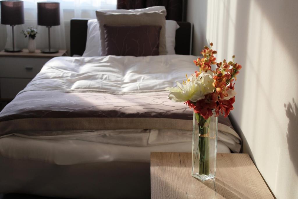 un jarrón de flores en una mesa junto a una cama en Mokka Apartments en Miskolc