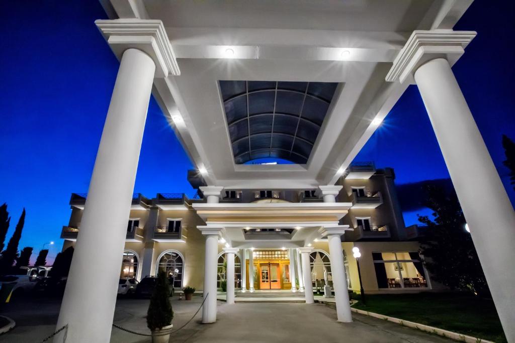 un grand bâtiment blanc avec colonnes la nuit dans l'établissement Kouros Hotel, à Dráma