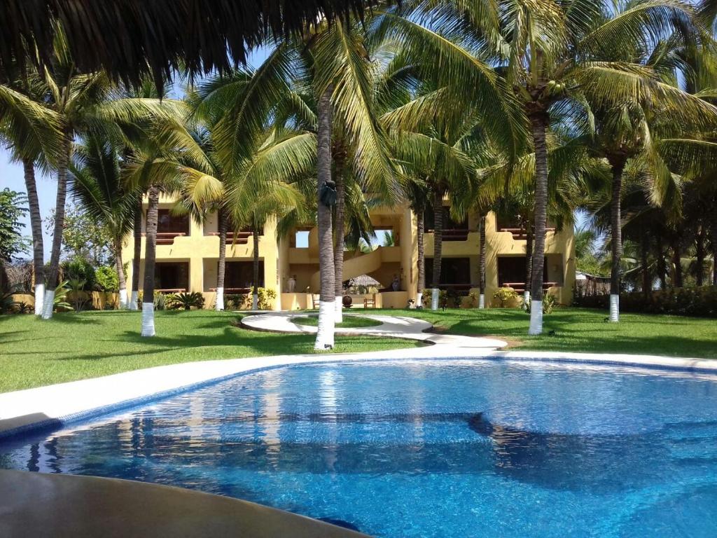 a swimming pool with palm trees in front of a building at Hotel Bella vista in Zihuatanejo