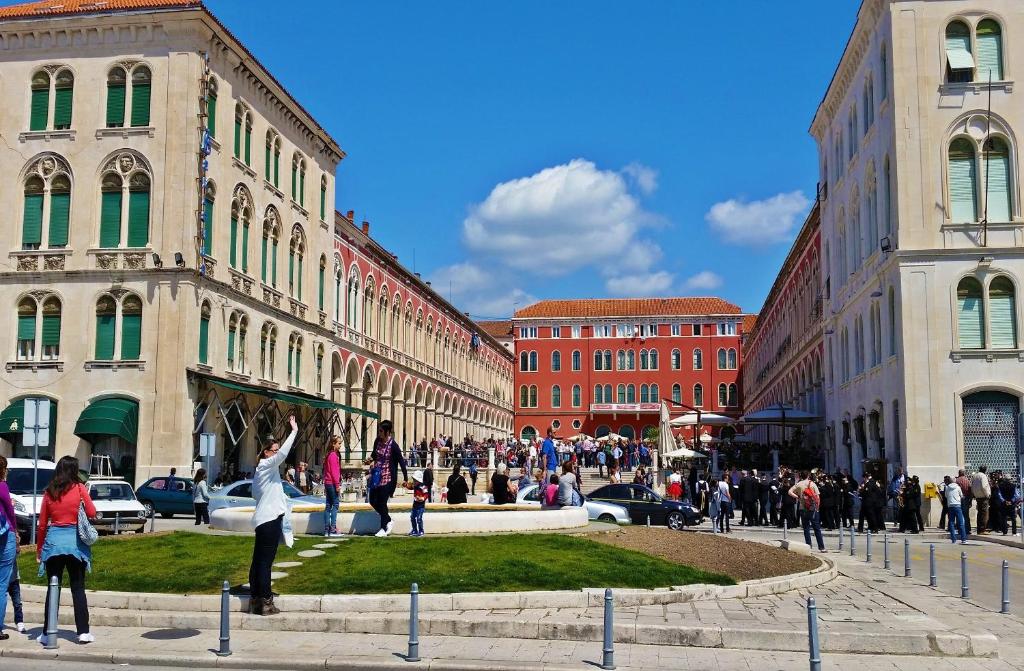 a group of people walking through a city with buildings at Apartments Emi in Split