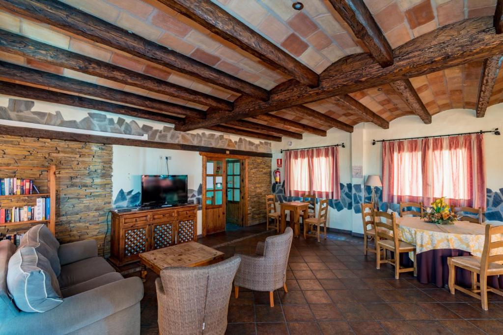 una sala de estar con techos de madera, mesas y sillas en Hotel Rural Almazara, en Frigiliana