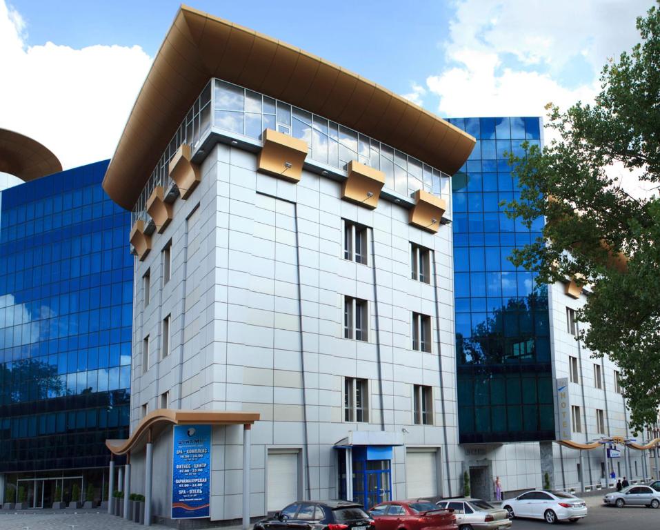 een wit gebouw met auto's ervoor geparkeerd bij Tsunami Spa Hotel in Dnipro