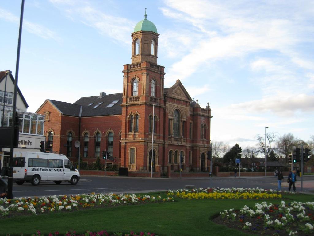 duży ceglany budynek z wieżą zegarową na ulicy w obiekcie Tees Valley Apartments w mieście Middlesbrough