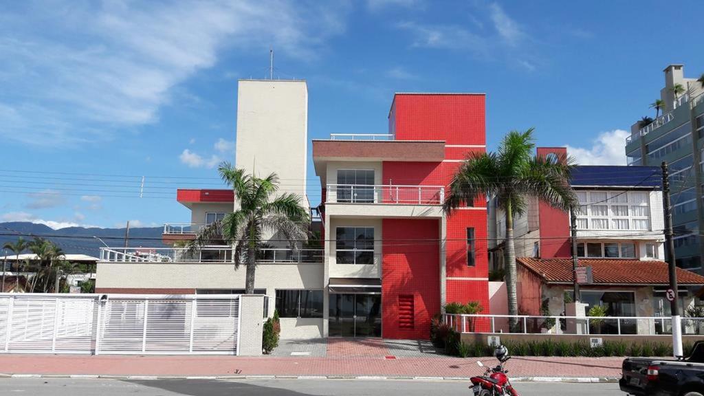 einem rot-weißen Gebäude mit Palmen davor in der Unterkunft Pousada e Restaurante Cantinho Oriental in Bertioga