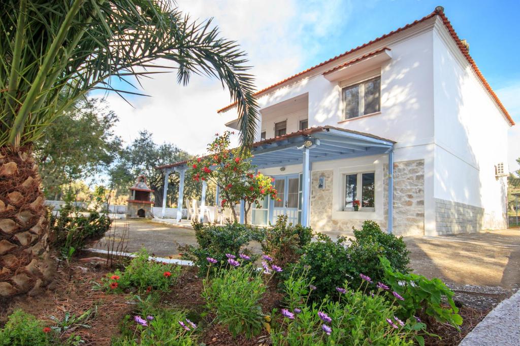 una casa blanca con una palmera y flores en Villa Valia, en Skala Kallirakhis