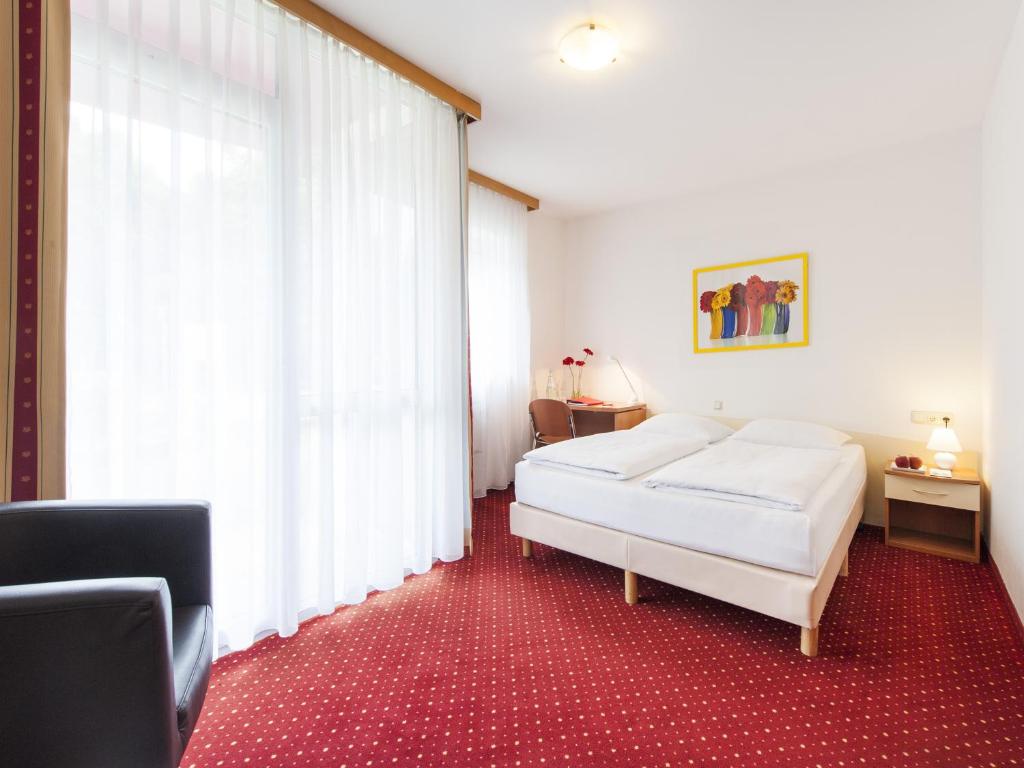 a bedroom with a bed and a large window at Andante Hotel Erding in Erding