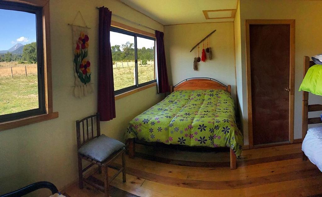 1 dormitorio con 1 cama, 1 silla y 1 ventana en Refugio de montaña El Huape en Curacautín