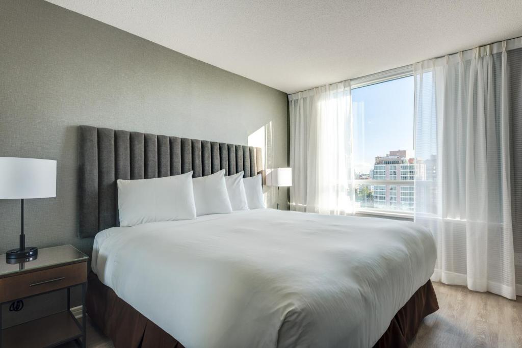 a large bed in a hotel room with a large window at Carmana Hotel & Suites in Vancouver